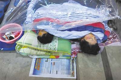 昨晚，宝兴县安置点，两位睡在操场看台的灾民将塑料布盖在被子外面阻挡湿冷。